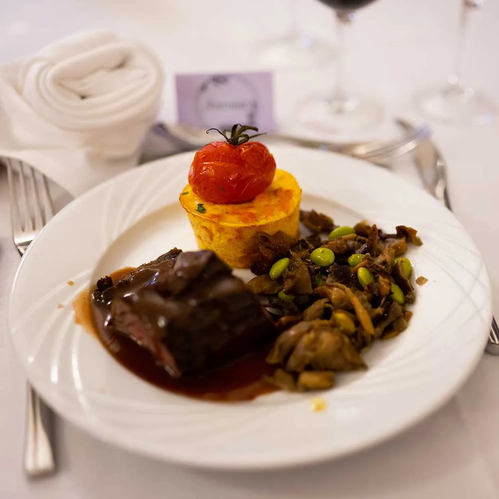 Pièce de bœuf, légumes glacés et tomate rôtie dressés à l’assiette, C le traiteur